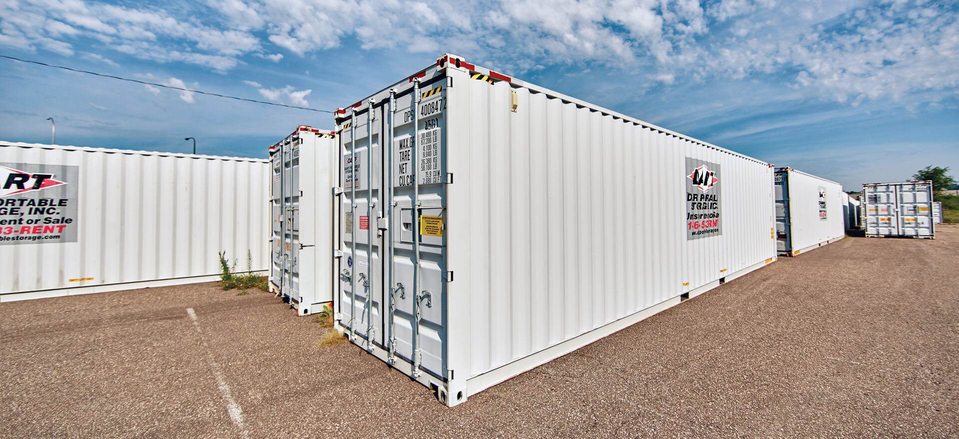 White Dart Portable Storage containers lined up on gravel lot under blue sky